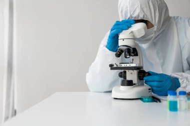 Laboratuvarda çalışmak için koruyucu maske takan Asyalı bilim adamı test tüpleri, kimya laboratuvarında mikroskop. geliştirme ve araştırma