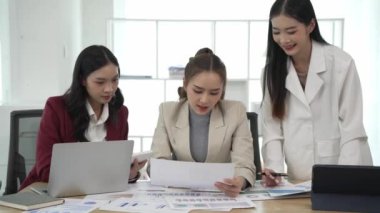 Gülümseyen Asyalı iş kadını iş arkadaşlarıyla konuşuyor ve ofiste fikir alışverişinde bulunuyor. Konferans odasında gülen kadın danışman ve dizüstü bilgisayarla fikir alışverişinde bulunuyor. Yeni iş fikri.