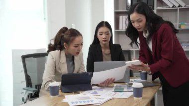 Gülümseyen Asyalı iş kadını iş arkadaşlarıyla konuşuyor ve ofiste fikir alışverişinde bulunuyor. Konferans odasında gülen kadın danışman ve dizüstü bilgisayarla fikir alışverişinde bulunuyor. Yeni iş fikri.