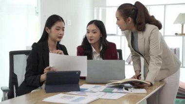 Gülümseyen Asyalı iş kadını iş arkadaşlarıyla konuşuyor ve ofiste fikir alışverişinde bulunuyor. Konferans odasında gülen kadın danışman ve dizüstü bilgisayarla fikir alışverişinde bulunuyor. Yeni iş fikri.