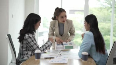 Gülümseyen Asyalı iş kadını iş arkadaşlarıyla konuşuyor ve ofiste fikir alışverişinde bulunuyor. Konferans odasında gülen kadın danışman ve dizüstü bilgisayarla fikir alışverişinde bulunuyor. Yeni iş fikri.