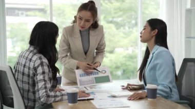 Gülümseyen Asyalı iş kadını iş arkadaşlarıyla konuşuyor ve ofiste fikir alışverişinde bulunuyor. Konferans odasında gülen kadın danışman ve dizüstü bilgisayarla fikir alışverişinde bulunuyor. Yeni iş fikri.