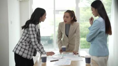 Gülümseyen Asyalı iş kadını iş arkadaşlarıyla konuşuyor ve ofiste fikir alışverişinde bulunuyor. Konferans odasında gülen kadın danışman ve dizüstü bilgisayarla fikir alışverişinde bulunuyor. Yeni iş fikri.