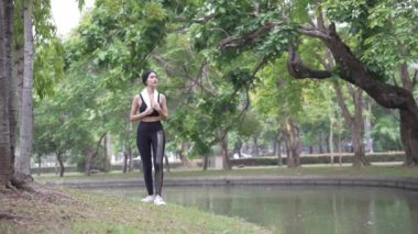 Çekici Asyalı kadın spor kıyafetleriyle bir yaz sabahı parkta koşuyor, açık hava aktivitelerinden hoşlanıyor, spor antrenmanlarından keyif alıyor..