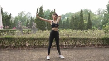 Çekici Asyalı kadın spor kıyafetleriyle bir yaz sabahı parkta koşuyor, açık hava aktivitelerinden hoşlanıyor, spor antrenmanlarından keyif alıyor..