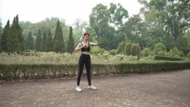 Çekici Asyalı kadın spor kıyafetleriyle bir yaz sabahı parkta koşuyor, açık hava aktivitelerinden hoşlanıyor, spor antrenmanlarından keyif alıyor..