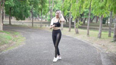 Çekici Asyalı kadın spor kıyafetleriyle bir yaz sabahı parkta koşuyor, açık hava aktivitelerinden hoşlanıyor, spor antrenmanlarından keyif alıyor..