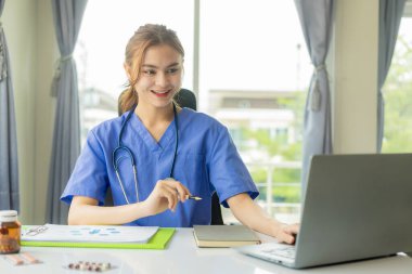 Dizüstü bilgisayarla çalışan genç ve güzel bir bayan doktor. Elektronik tıbbi kayıtları okuyun. Doktorlar hastalara sanal konsültasyonlar sağlarlar..