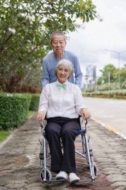 Mutlu Asyalı yaşlı çift tropikal bir orman yolunda birlikte yürüyor emekli yaşlı adam ve kadın eğleniyor ve açık hava seyahatlerinin tadını çıkarıyor. Dikey resim