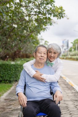 Mutlu Asyalı yaşlı çift tropikal bir orman yolunda birlikte yürüyor emekli yaşlı adam ve kadın eğleniyor ve açık hava seyahatlerinin tadını çıkarıyor. Dikey resim