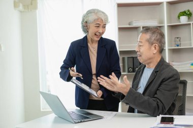 İki üst düzey Asyalı işadamı mali durumu belgelerle analiz ediyor. Erkek ve kadın analiz ve hesaplama için finansal belgeler üzerinde çalışıyorlar. İşte mutlu görün..