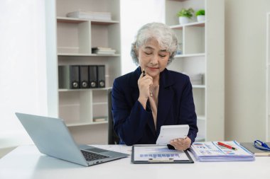 Yeni işletmeleri analiz eden kıdemli Asyalı iş kadını yeni mali yatırımları tartışmak ve planlamak için ortaklarla internette buluş.