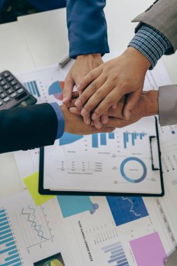 İş adamlarının el sıkışması ve yukarıdaki belgelerle bir ortak tutmak ya da ofiste birlikte çalışmak için toplanması. Yakın çekim pazarlama projesinin takım çalışması veya araştırması