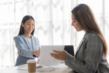İki Asyalı iş kadını ofisteki dizüstü bilgisayarlarda raporlarla birlikte çalışıyor. Meslektaşlar yeni pazarlama projelerinin belge analizinde mali verileri tartıştılar.
