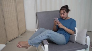 İnternette cep telefonuyla gezinen mutlu Asyalı genç bir kadın, İnternet üzerinden alışveriş yapıyor..