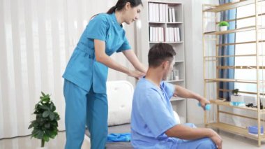 Bir hemşire, erkek bir hastaya hastanede fizik tedavi uygulamaya yardımcı olur. Asyalı erkek hasta, sağlık sigortası konseptinde tedavi görüyor