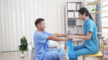 Bir hemşire, erkek bir hastaya hastanede fizik tedavi uygulamaya yardımcı olur. Asyalı erkek hasta, sağlık sigortası konseptinde tedavi görüyor