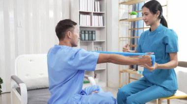 Bir hemşire, erkek bir hastaya hastanede fizik tedavi uygulamaya yardımcı olur. Asyalı erkek hasta, sağlık sigortası konseptinde tedavi görüyor
