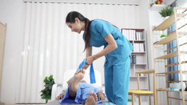 Bir hemşire, erkek bir hastaya hastanede fizik tedavi uygulamaya yardımcı olur. Asyalı erkek hasta, sağlık sigortası konseptinde tedavi görüyor