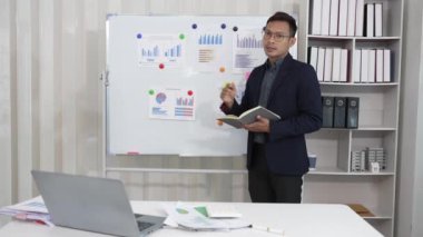 Asyalı iş adamı ve kadın belgeler, finansal grafikler ve danışmanlık bilgisayarlarıyla meşguller. Akıllı planlama meslektaşları iş problemlerini tartışır ofiste otururken tavsiye verir