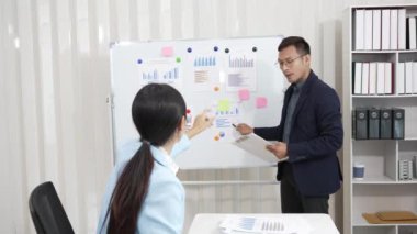 Asyalı iş adamı ve kadın belgeler, finansal grafikler ve danışmanlık bilgisayarlarıyla meşguller. Akıllı planlama meslektaşları iş problemlerini tartışır ofiste otururken tavsiye verir