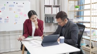 Asyalı iş adamı ve kadın belgeler, finansal grafikler ve danışmanlık bilgisayarlarıyla meşguller. Akıllı planlama meslektaşları iş problemlerini tartışır ofiste otururken tavsiye verir