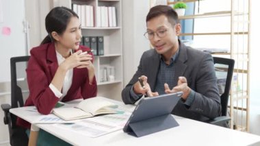 Asyalı iş adamı ve kadın belgeler, finansal grafikler ve danışmanlık bilgisayarlarıyla meşguller. Akıllı planlama meslektaşları iş problemlerini tartışır ofiste otururken tavsiye verir