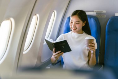 Uçakta oturan ve pencereden dışarı bakan Asyalı kadın, seyahat konsepti, turizm, iş