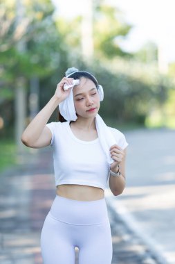 Şehir parkında koştuktan ya da koştuktan sonra bacaklarını esneten bir kadın. İyi sağlık için, doğa parkında serinletici bir koşuya çıkmadan önce ısının. Antrenmandan sonra Asyalı koşucu