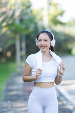 Şehir parkında koştuktan ya da koştuktan sonra bacaklarını esneten bir kadın. İyi sağlık için, doğa parkında serinletici bir koşuya çıkmadan önce ısının. Antrenmandan sonra Asyalı koşucu