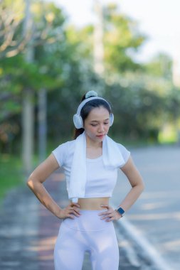 Şehir parkında koştuktan ya da koştuktan sonra bacaklarını esneten bir kadın. İyi sağlık için, doğa parkında serinletici bir koşuya çıkmadan önce ısının. Antrenmandan sonra Asyalı koşucu