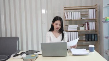 Dizüstü bilgisayarda çalışan ve evrak işleriyle uğraşan kadın muhasebeci, vergiler, ticaret, araştırma, muhasebe ve muhasebe analizleri, gayrimenkul yatırım verileri, finansmanlar