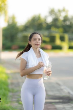 Sağlıklı Asyalı kadın egzersiz yapmadan önce sağlıklı spor içecekleriyle susuzluğunu giderir. Dikey resim.