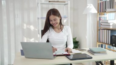 Ofiste çalışan Asyalı güzel bir kadın fotokopi şirketi sahipleri bilgisayar kullanarak online pazarlama yapıyor..