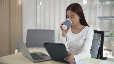 Ofiste çalışan Asyalı güzel bir kadın fotokopi şirketi sahipleri bilgisayar kullanarak online pazarlama yapıyor..