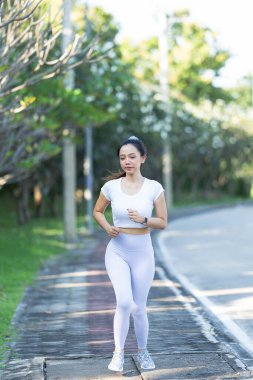 Asya spor parkında sabah sporu yapan güzel bir Asyalı bayan koşucu. Güzellik. Spor kıyafetlerle sıska vücut ısınıyor. Rahatla ve kaslarını esneterek spor yap..