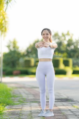 Asya spor parkında sabah sporu yapan güzel bir Asyalı bayan koşucu. Güzellik. Spor kıyafetlerle sıska vücut ısınıyor. Rahatla ve kaslarını esneterek spor yap..