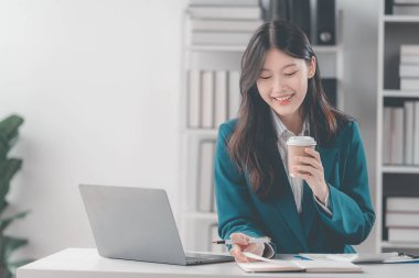 Bilgisayarla çalışan Asyalı kadın vergi, muhasebe, istatistik ve analitik araştırma kavramları üzerinde çalışıyor. İş verilerini, mali muhasebe kavramlarını hesaplamak için bir hesap makinesi ile tamamlanmış.