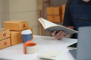 Küçük bir işletme kuran işletme sahibi, bir karton kutuya adres yazıyor, küçük işletme girişimcisi, KOBİ evde kutularla çalışıyor, internette satıyor, yakın plan fotoğraf satıyor