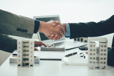 Müşteriler ve ev satış temsilcileriyle el sıkışırken ajan ve müşterilerin el sıkışması kontrat imzalandıktan sonra yeni bir daire satın almak..