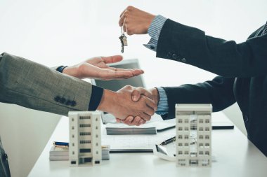Müşteriler ve ev satış temsilcileriyle el sıkışırken ajan ve müşterilerin el sıkışması kontrat imzalandıktan sonra yeni bir daire satın almak..