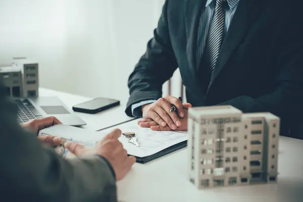 Emlakçı Apartman Satıcısı müşterilere ev ve konut satışı için yakın plan resimleri imzalama sözleşmesi imzalama teklifinde bulundu.