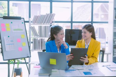 Başarılı Asyalı iş kadını takım toplantısını sunuyor ve ofiste fikirlerini sunuyor.