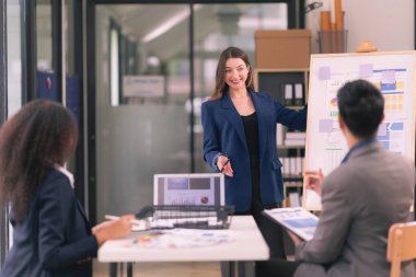 Asyalı başarılı iş adamlarından oluşan bir ekip takım toplantı dakikalarını ve ofis işbirliği fikirlerini sunuyor..