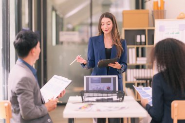 Asyalı başarılı iş adamlarından oluşan bir ekip takım toplantı dakikalarını ve ofis işbirliği fikirlerini sunuyor..