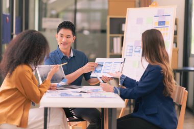 Asyalı başarılı iş adamlarından oluşan bir ekip takım toplantı dakikalarını ve ofis işbirliği fikirlerini sunuyor..