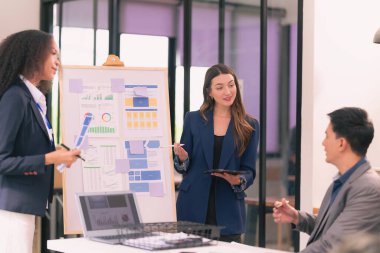 Asyalı başarılı iş adamlarından oluşan bir ekip takım toplantı dakikalarını ve ofis işbirliği fikirlerini sunuyor..