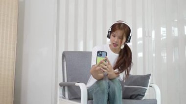 Şirin Asyalı kadın mutlu bir şekilde gülümsüyor, akıllı telefon kullanmaktan hoşlanıyor, internette, sosyal medyada, rahatlatıcı, günlük hayatta teknoloji.