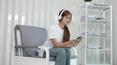 Şirin Asyalı kadın mutlu bir şekilde gülümsüyor, akıllı telefon kullanmaktan hoşlanıyor, internette, sosyal medyada, rahatlatıcı, günlük hayatta teknoloji.