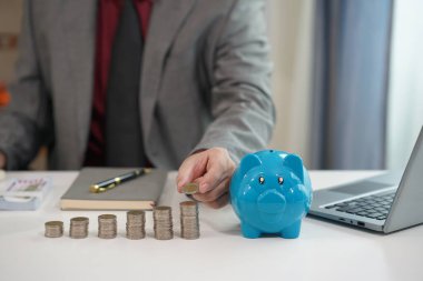 İşadamı, emlak yatırımının sembolü olan banka, ev ve araba hesaplarına para tasarrufu yapmak için kumbaraya bozuk para koyuyor. Fotoğrafı kapat..